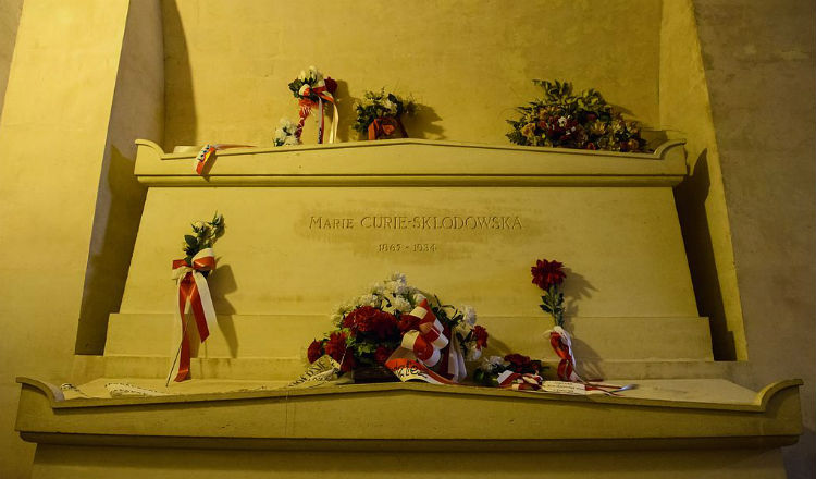 Marie Curie wordt begraven in een met loden beklede doodskist. Haar lichaam en aantekeningen zijn zeer radioactief omdat ze met radium werkte.